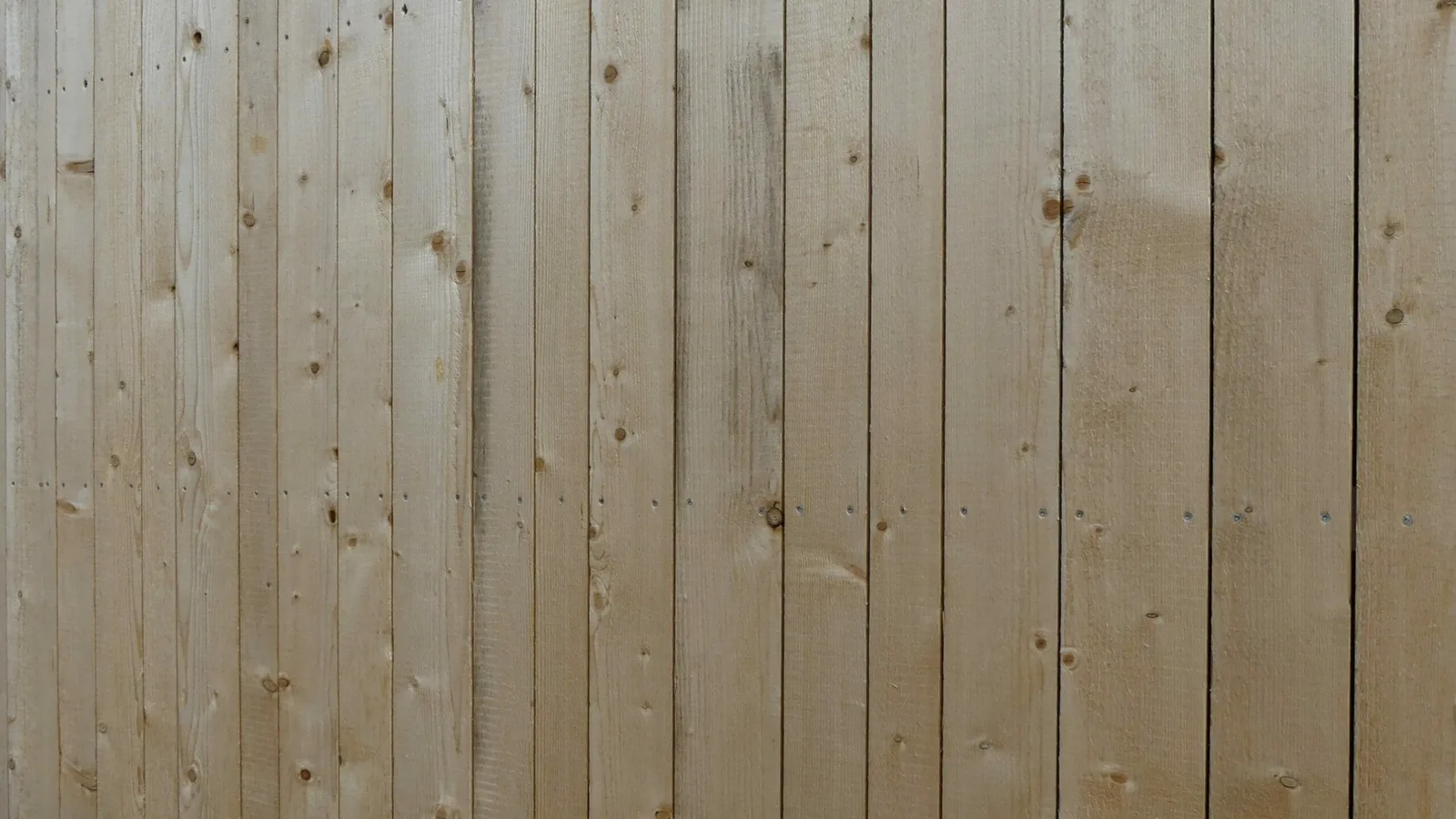 Fassade aus senkrechten Brettern in verschiedenen Breiten, die Holzstruktur und die Astbilder gut sichtbar